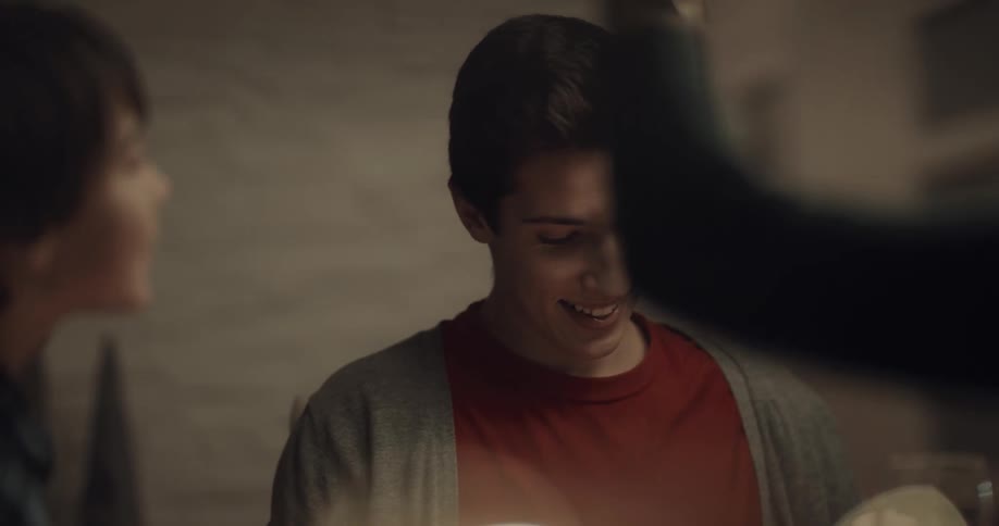 A woman takes a selfie with her phone as she eats with her family