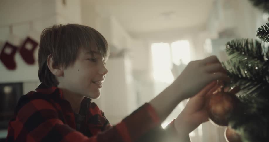 A young boy places an ornament on a christmas tree