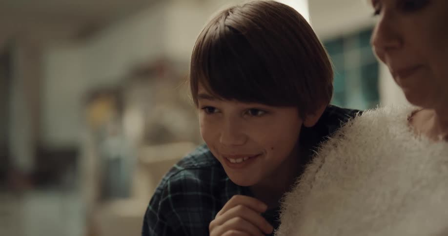 A young boy leans against his grandmother and talks with her