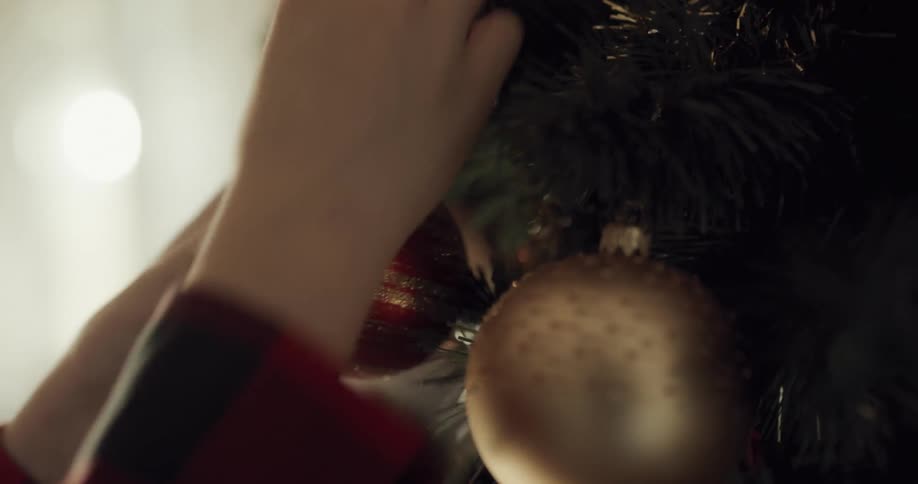 Boy decorates the christmas tree with christmas tree lights and christmas bulbs