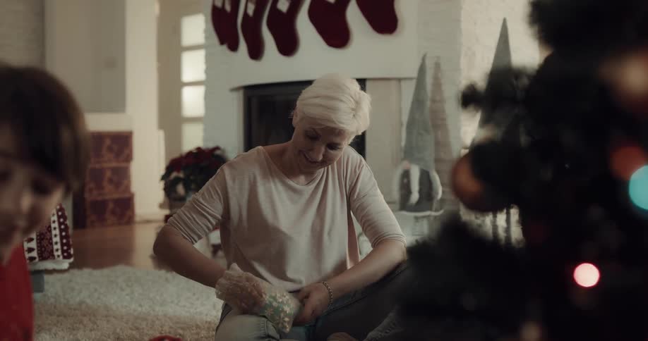 Grandson hands gift to grandmother and she hugs him