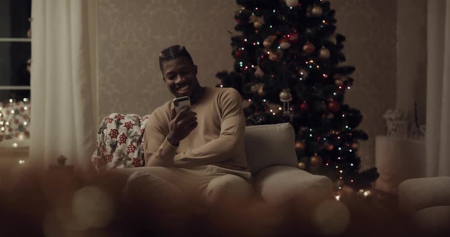 Man sits on chair near christmas tree to make a video call