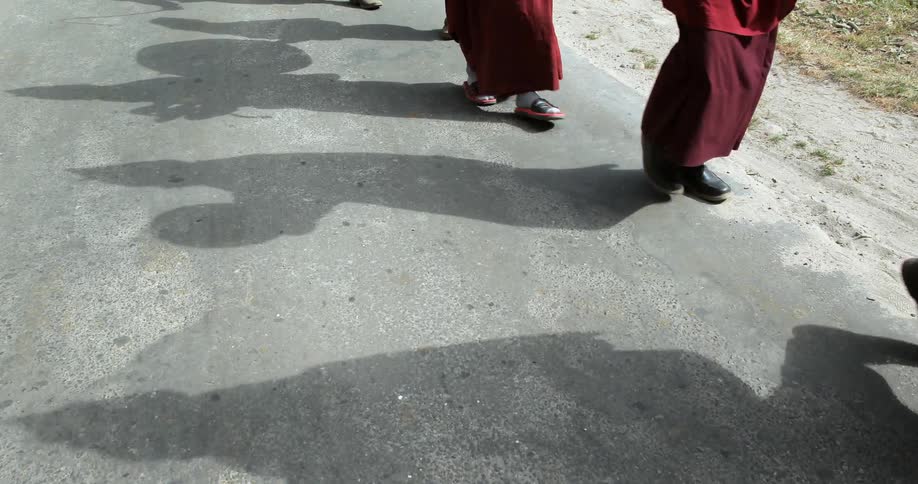 People in red robes walking single file down a road