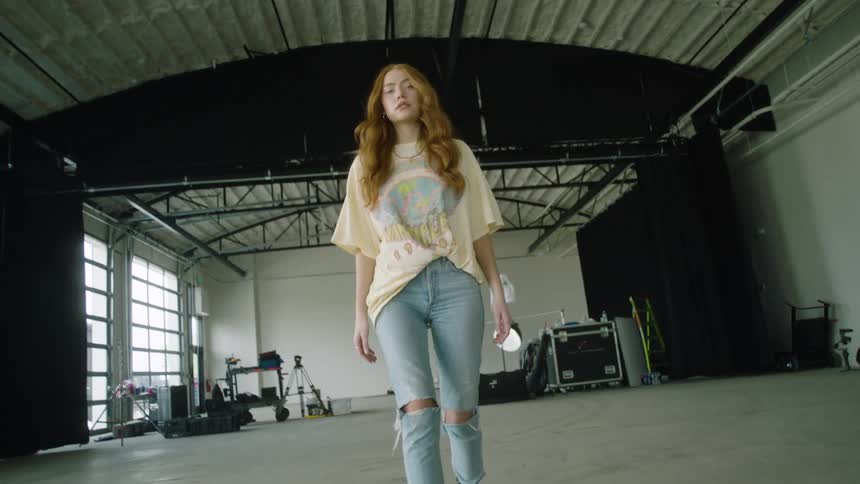 A caucasian woman walking backgrounds while posing for the camera in a warehouse