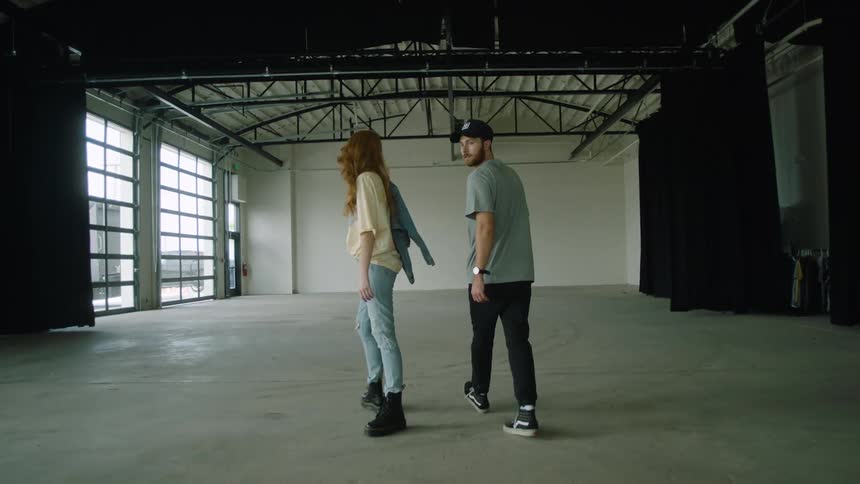 A man and woman are walking in an empty room