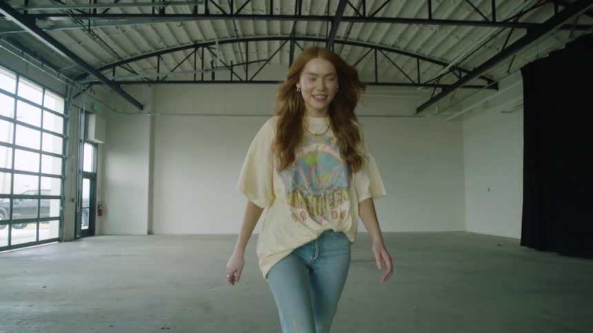 A teenage girl walks through an empty warehouse
