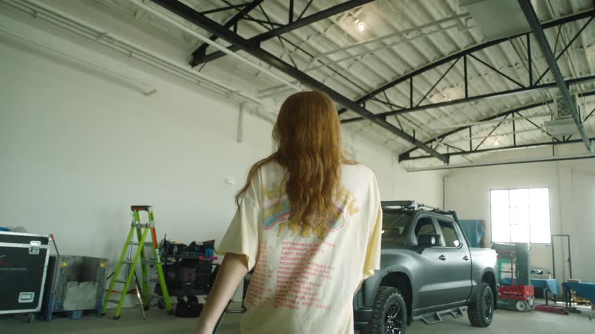 A man films a woman walking and turning in a building