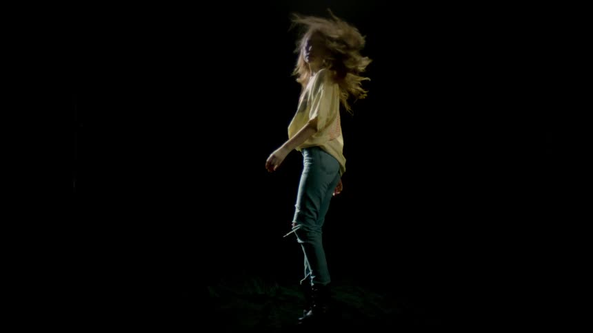 Woman with long hair and wearing jeans spins around causing her hair to fly in the air
