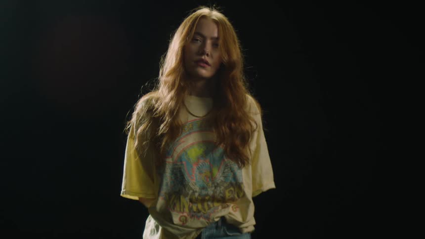Woman with long red hair poses against black background