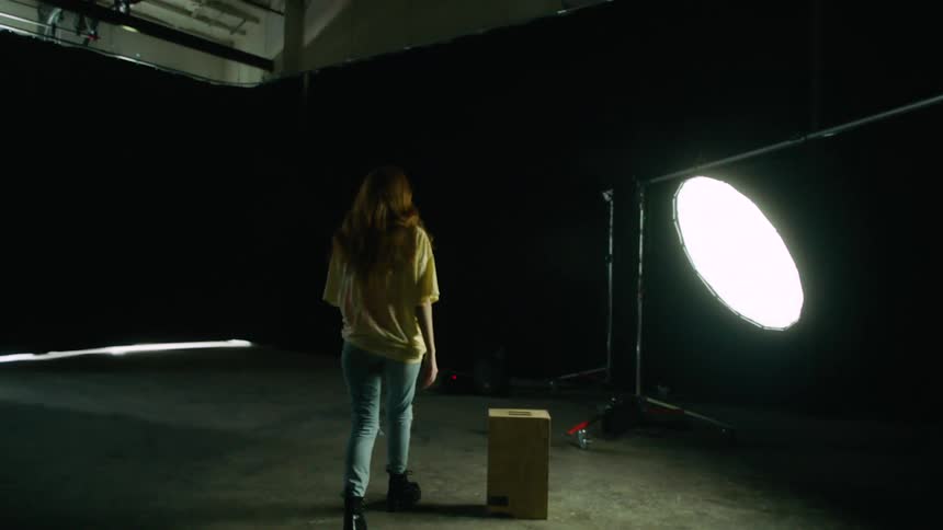 A teenage girl walks to a light set up for a photo shoot