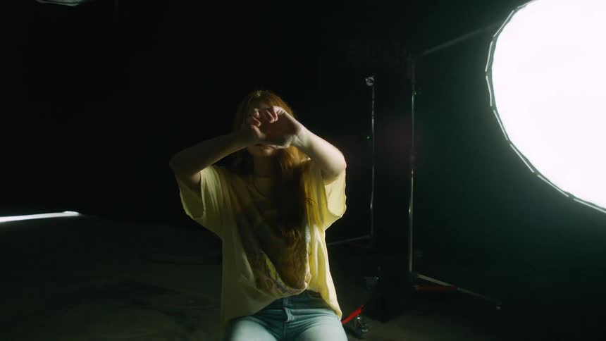 A woman is posing in front of a large light