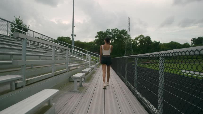 A woman walks past the bleachers in the park