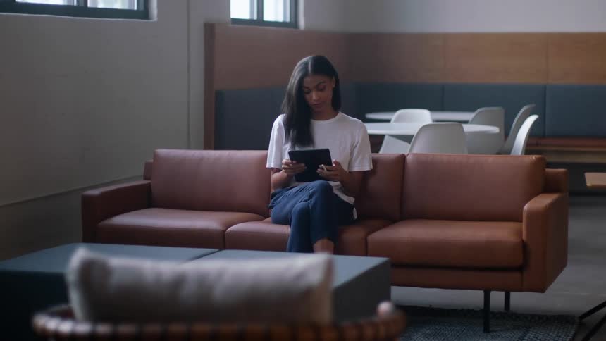 Woman sitting on couch looking at tablet