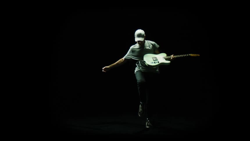 A man is playing guitar while wearing a hat