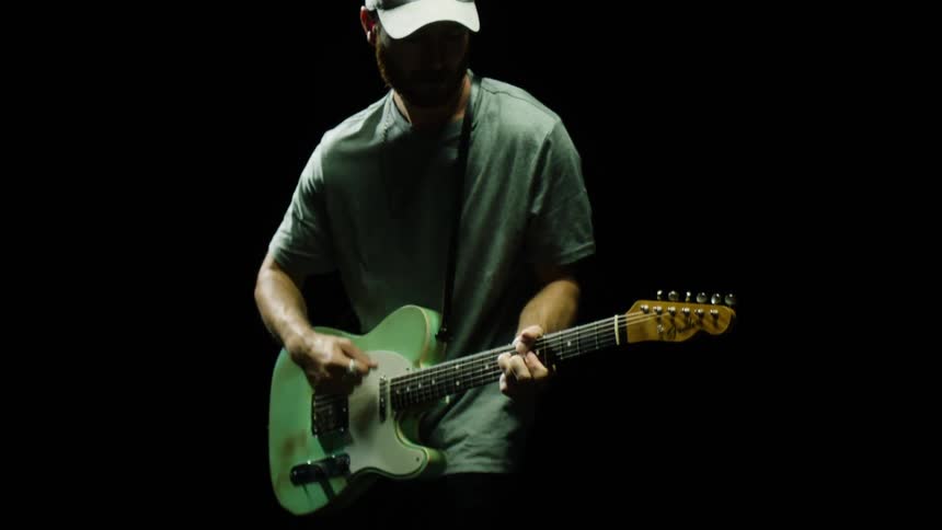 Man playing his guitar in a dark room