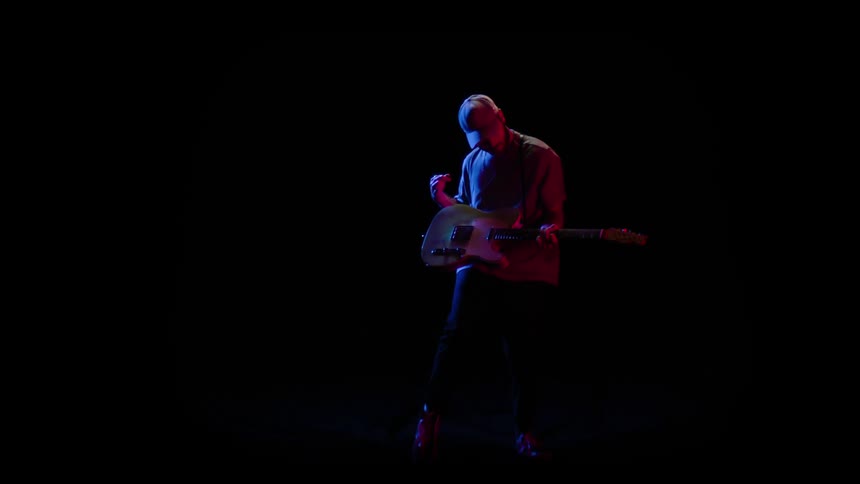 A man is playing guitar in an empty room