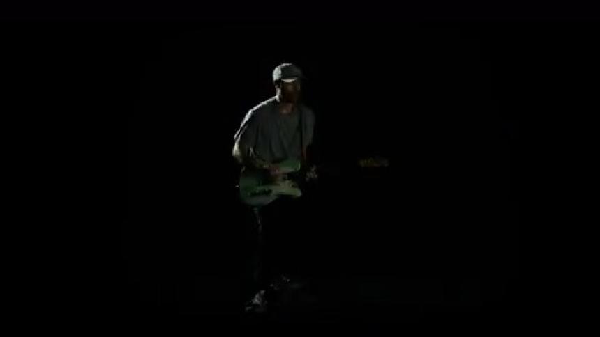 A man is playing guitar while wearing a hat