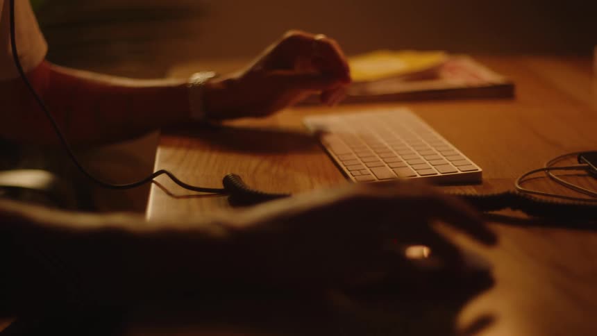 Man typing on an apple computer on top of a wooden table