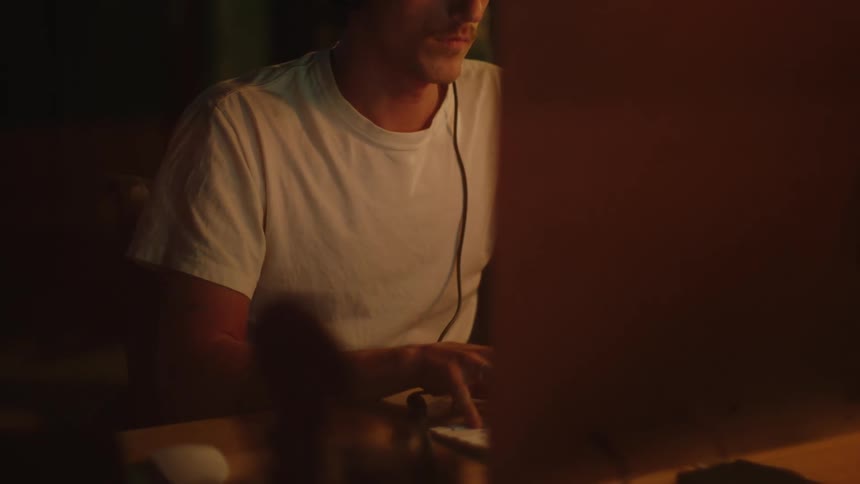 A man is typing on a computer indoors at night