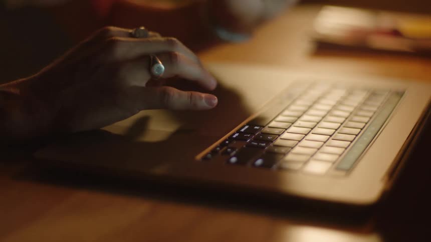 A person typing on a laptop computer at a table