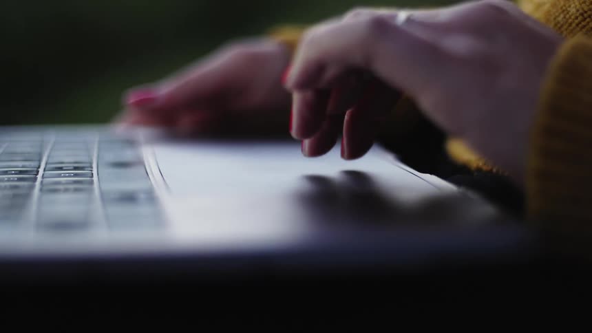 Woman using the touchpad of a laptop in a dimly lit room