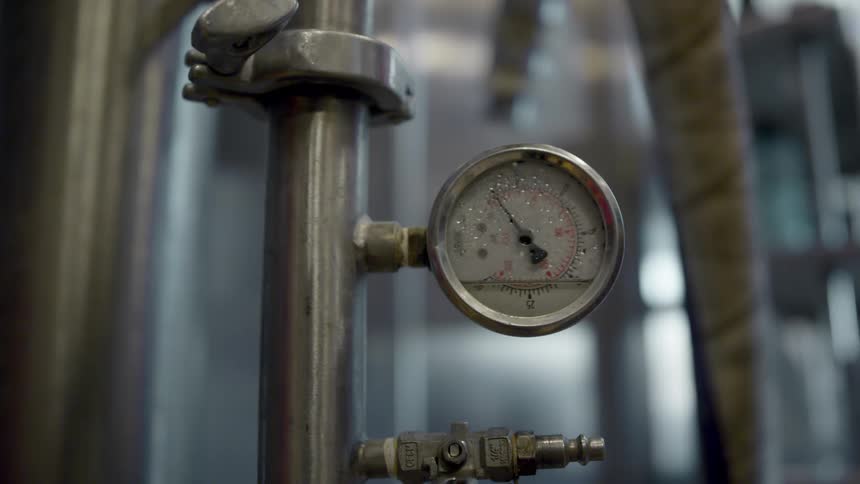 A close up with a metal pipe and an attached gauge