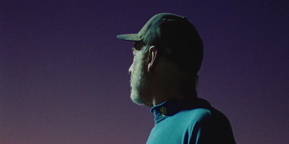 Sports coach wearing a hat looking at the sky at night