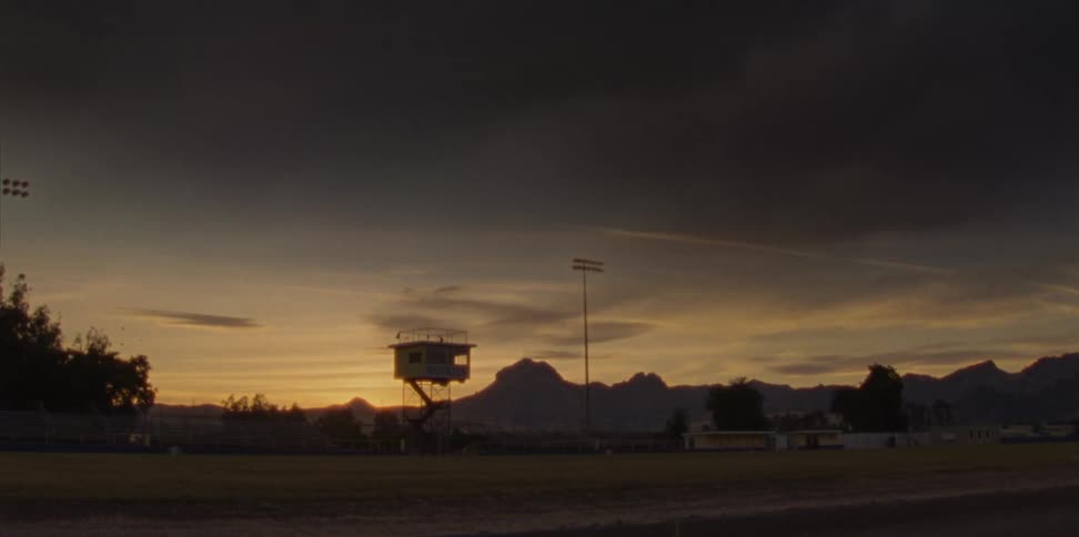 A field with with stadium lights and lightning above