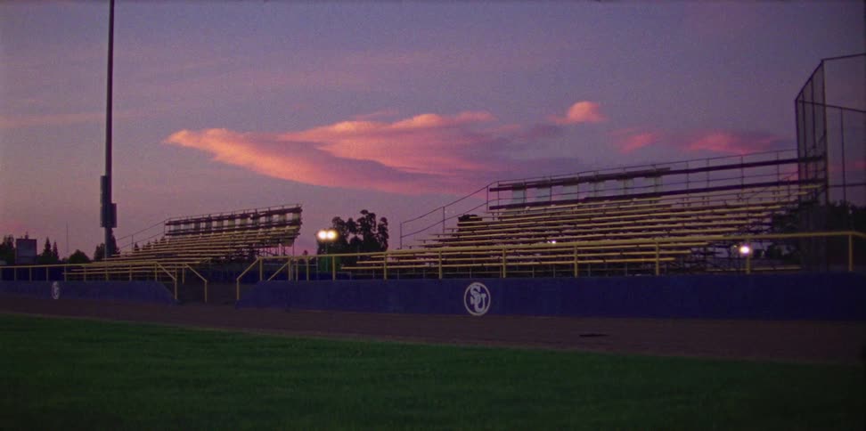 A sports field at dusk with stands in the background
