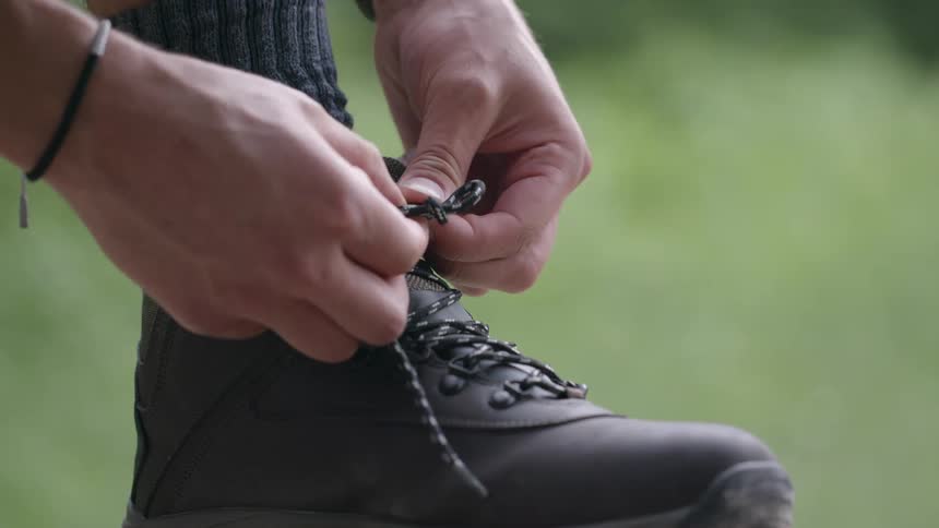 A person is tying their shoes outdoors in spring