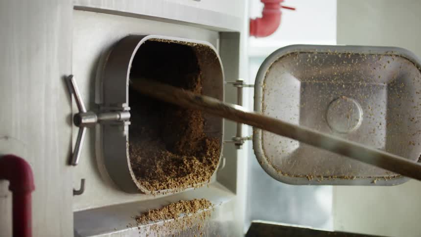 A person with a tool removing brown debris from an oven