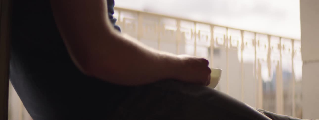 A man relaxing on his balcony taking a sip of his beverage