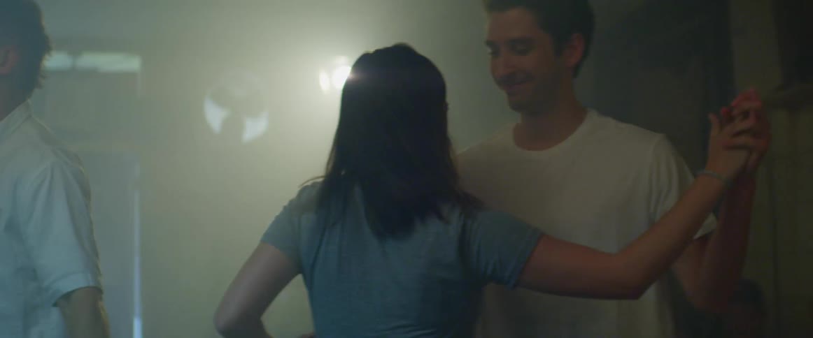 A young man and woman dance next to a pool table in a pub during the day