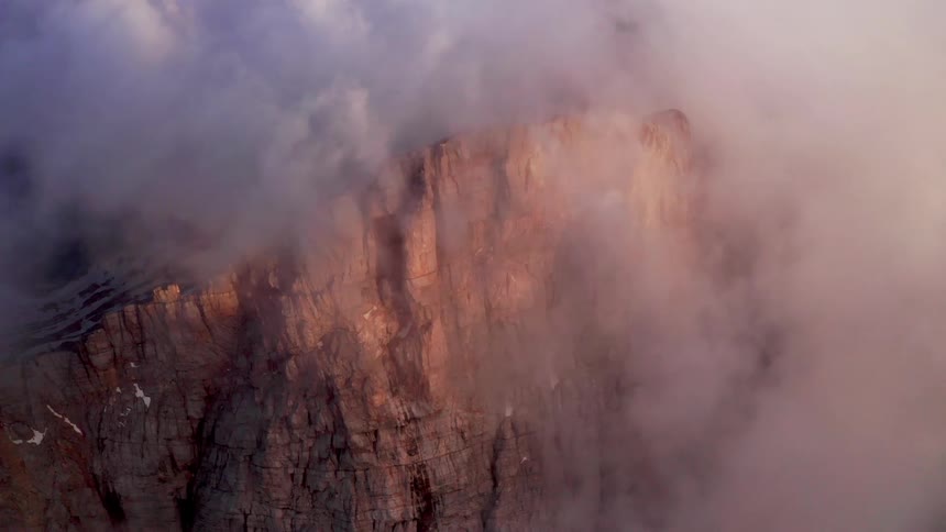 Clouds floating around a rocky cliffside in the wilderness