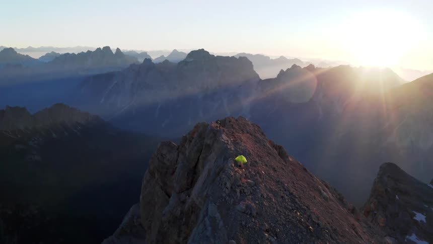 A person standing in front of a cross on top of a mountain range