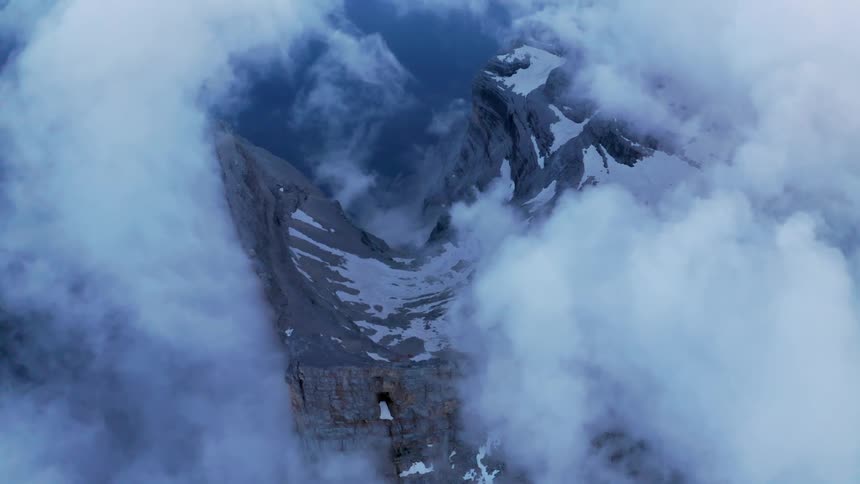 White clouds surrounding a mountain with snow