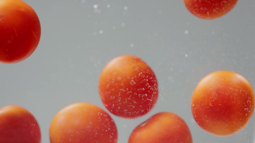 Oranges falling into water with bubbles with a gray background