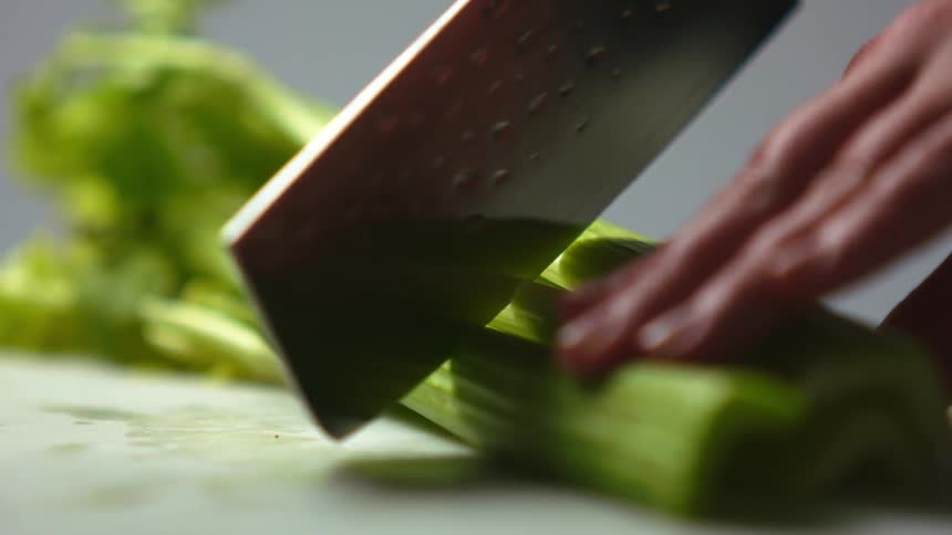 A woman cuts celery in half