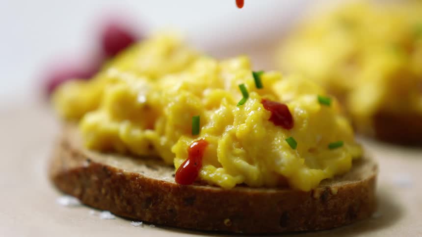 Ketchup is added to scrambled eggs topping bread slices