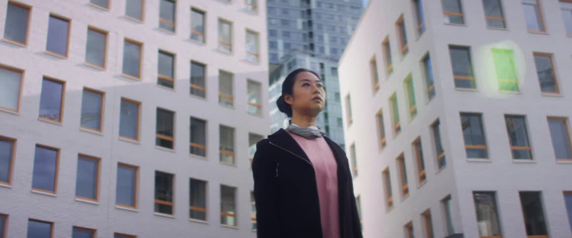 A woman stops to take off her mask and look at the city