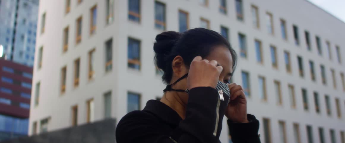 A woman is putting on a face mask outdoors