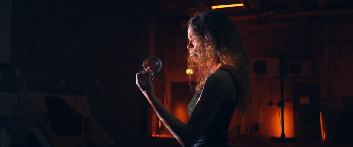 Young woman holding a lens on her hand in a dimly lit room