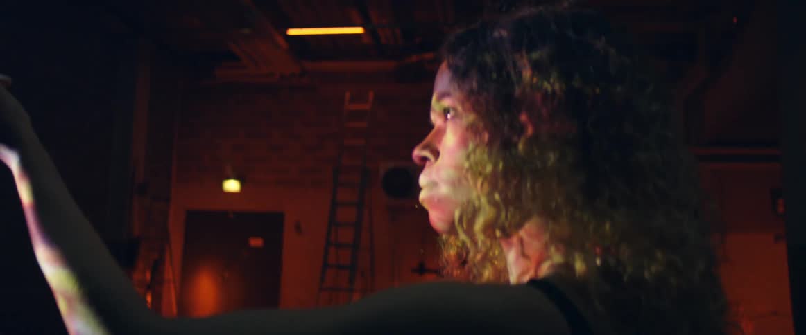 Woman stands in front of projector examining prism in room
