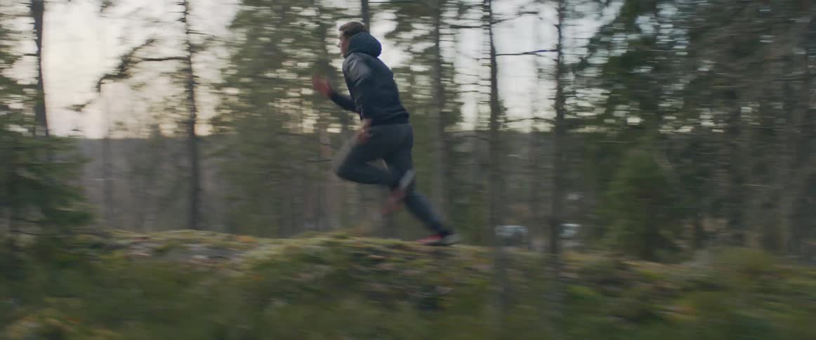Man in a sport apparel is running through the forest