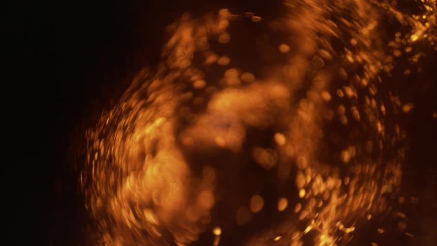Bubbles shift around and collapse on each other within an amber liquid