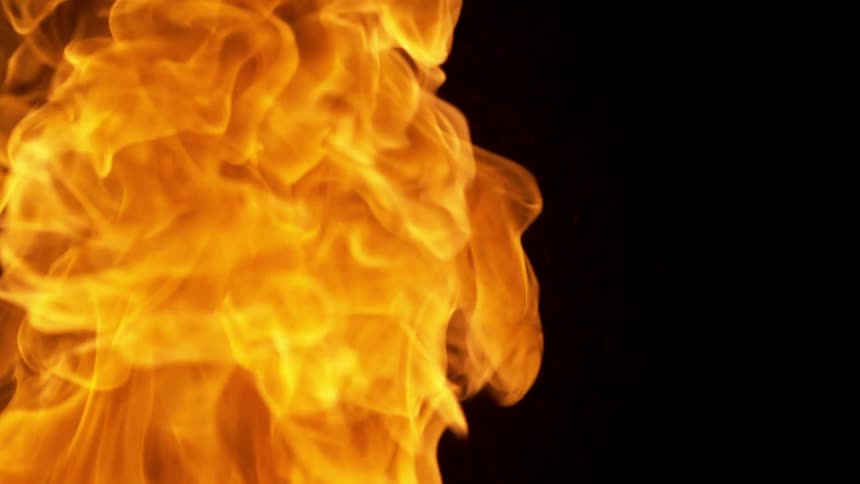 A lone wispy orange fire plume slowly drifts upwards surrounded by blank darkness