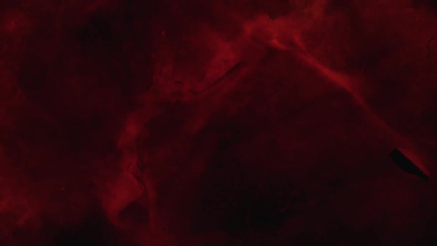 Red ink poured spreading in water over a surface