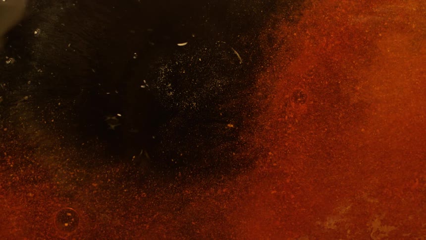 Red ink particles spreading flowing over water