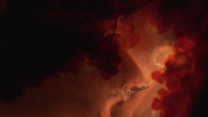 A crystal like substance appears submerged in some liquid as splashes of red are added in in large amounts