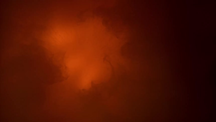A light glows red under a thin membrane seen through a microscope